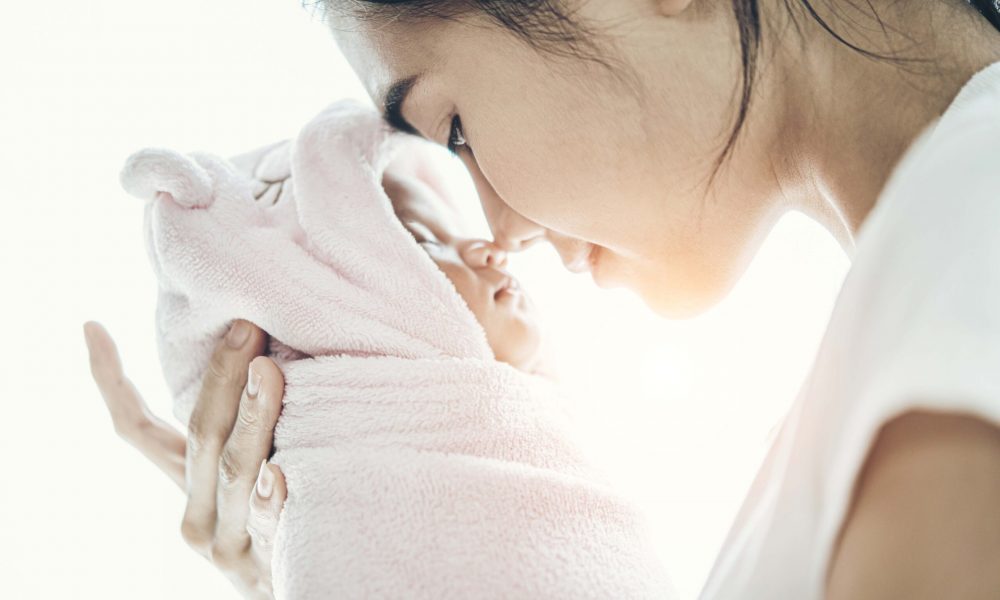 The newborn baby sleeping in the hands of the mother and the nose collided.